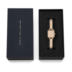 Daniel WellingtonのQuadro Mini Reflection Rose Goldは、ネイビーのブランドロゴ入りギフトボックスに収められています。黒いクッションケースの上に、ローズゴールドのミラーダイヤルとメッシュストラップが映える、贈り物にぴったりの上品なパッケージです。