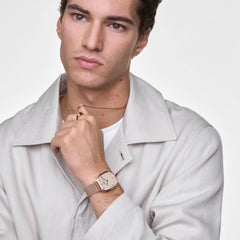 Marlon Wire Linen Rose Goldを着用した男性モデルのスタイルです。ライトグレーのジャケットに白のTシャツ、ローズゴールドのクッション型ケースとワイヤーメッシュバンドが上品に調和し、落ち着いた大人の雰囲気を演出します。