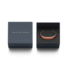 Emalie Bracelet Cherry Blush Rose Goldがダークネイビーのギフトボックスに収められた様子です。ブランドロゴ入りの蓋が左側に置かれ、右側の箱の中にはチェリーブラッシュエナメルとローズゴールドのカフブレスレットが黒いクッションカバーの上に丁寧にセットされています。