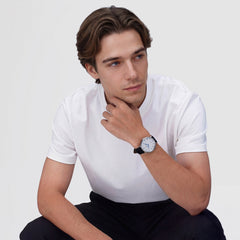 白いTシャツにダークパンツを合わせた男性が、Classic Roman Numerals Date Black Croc Belly Silverを着用したスタイリングイメージです。ブラックのレザーストラップとシルバーケースが、カジュアルな装いにも自然になじみます。