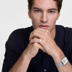 男性モデルがダークネイビーのニットを着用し、左手首にはDaniel WellingtonのMarlonシルバーメッシュ腕時計、右手の薬指にはClassic Mini Signet Ringシルバーを合わせたスタイリングです。シルバートーンで統一された上品な手元のコーディネートです。