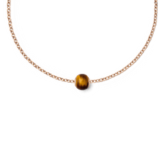 ローズゴールドのチェーンネックレスに通したTiger Eye Orbチャームのスタイリング例です。天然のタイガーアイ特有の琥珀色とブラウンの縞模様が、細身のチェーンの中央で上品なアクセントとなっています。