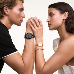 男女で合わせたペアスタイリング。女性はCrystal Link Bracelet Goldをゴールドの腕時計やリングと重ね付けし、男性はブラックの腕時計を身に着けています。ギフトシーンをイメージしたビジュアルです。