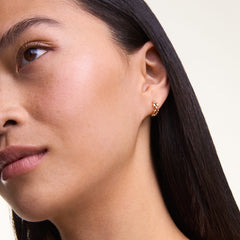 ダニエルウェリントンの3-Link Earrings ローズゴールドを着用した女性の耳元をクローズアップ。小ぶりなリンクモチーフのフープピアスが、耳元に自然になじみ、上品なアクセントを添えます。