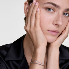 Classic Tennis Bracelet Honey Combo Goldを2本重ね付けした女性の着用イメージです。ブラックのサテンシャツに合わせ、ハニーカラーとクリアストーンの繊細な輝きが手元にさりげない華やかさを添えています。