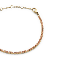 アプリコットゴールドのClassic Tennis Braceletをクローズアップ。淡いピーチトーンのプレシオサ・クリスタルがゴールドの爪留めで一粒ずつ丁寧にセットされ、サイズ調節リング付きのチェーン部分もご覧いただけます。