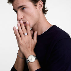 ネイビーのニットを着た男性がDaniel Wellington Classic Day Display Sterlingを着用した様子です。シャンパンカラーの文字盤とシルバーメッシュストラップが手首に自然になじみ、シルバーのリングやブレスレットと合わせることで上品な印象を演出します。