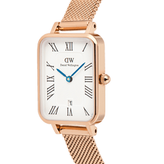 Quadro Melrose Roman Numerals Dateを斜めからクローズアップした画像です。ローズゴールドのケースに施された立体的なエッジライン、ギョーシェ模様の浮かぶホワイトダイヤル、IPブルーの時分針、リューズの細部、そしてメッシュストラップの繊細な編み目が確認できます。