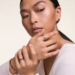 Daniel Wellingtonの3-Link Bracelet ローズゴールドを手首に着用した女性モデル。同じリンクコレクションのリングとイヤリングを合わせたコーディネートで、ローズゴールドの統一感ある輝きが際立ちます。
