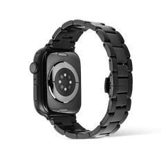 Daniel Wellington Smartwatch Iconic Link Onyxを装着したApple Watchを背面から撮影した画像です。センサー部分が見える裏蓋を中心に、ブラックPVDコーティングの3連リンクブレスレットがループ状に広がっています。手首側に向かってリンク幅が細くなるテーパードシルエットも確認できます。