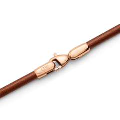 St Mawes Bracelet Rose Goldのクラスプ部分を拡大したディテール画像です。ローズゴールドのロブスタークラスプにはDaniel Wellingtonのロゴが刻印されており、ブラウンレザーコードとの接合部まで丁寧に仕上げられた質感がわかります。