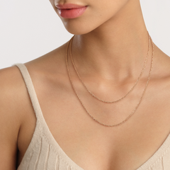 Daniel WellingtonのTwisted Chain Necklaceをローズゴールドで二連に重ね付けしたスタイルです。ベージュのニットキャミソールに合わせ、鎖骨まわりに繊細な輝きを演出しています。