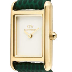 Bound Mini Green Lizard Goldの文字盤とケースをクローズアップした画像です。ポリッシュ仕上げのゴールド長方形ケースに、ゴールドの二針とDaniel Wellingtonロゴのみを配したミニマルなホワイト文字盤が収められています。右側にはゴールドのリューズが見え、グリーンのリザード型押しレザーストラップの鱗模様も確認できます。