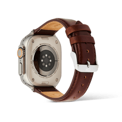 Apple Watch Ultraの裏面から見たDaniel Wellington Smartwatch Leather Strap St Mawesの装着イメージです。ブラウンのレザーストラップの内側にはナチュラルな素地が覗き、シルバーのピンバックルにはDaniel Wellingtonのロゴが刻印されています。
