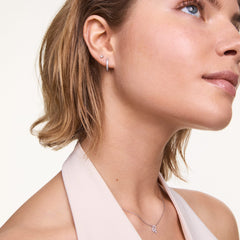 シルバーのCrystal Hoop Earringを着用した女性のクローズアップ。キュービックジルコニアが輝くフープピアスを耳たぶに、上のピアスホールにはスタッドピアスを重ね付けし、シルバーネックレスとコーディネートしています。