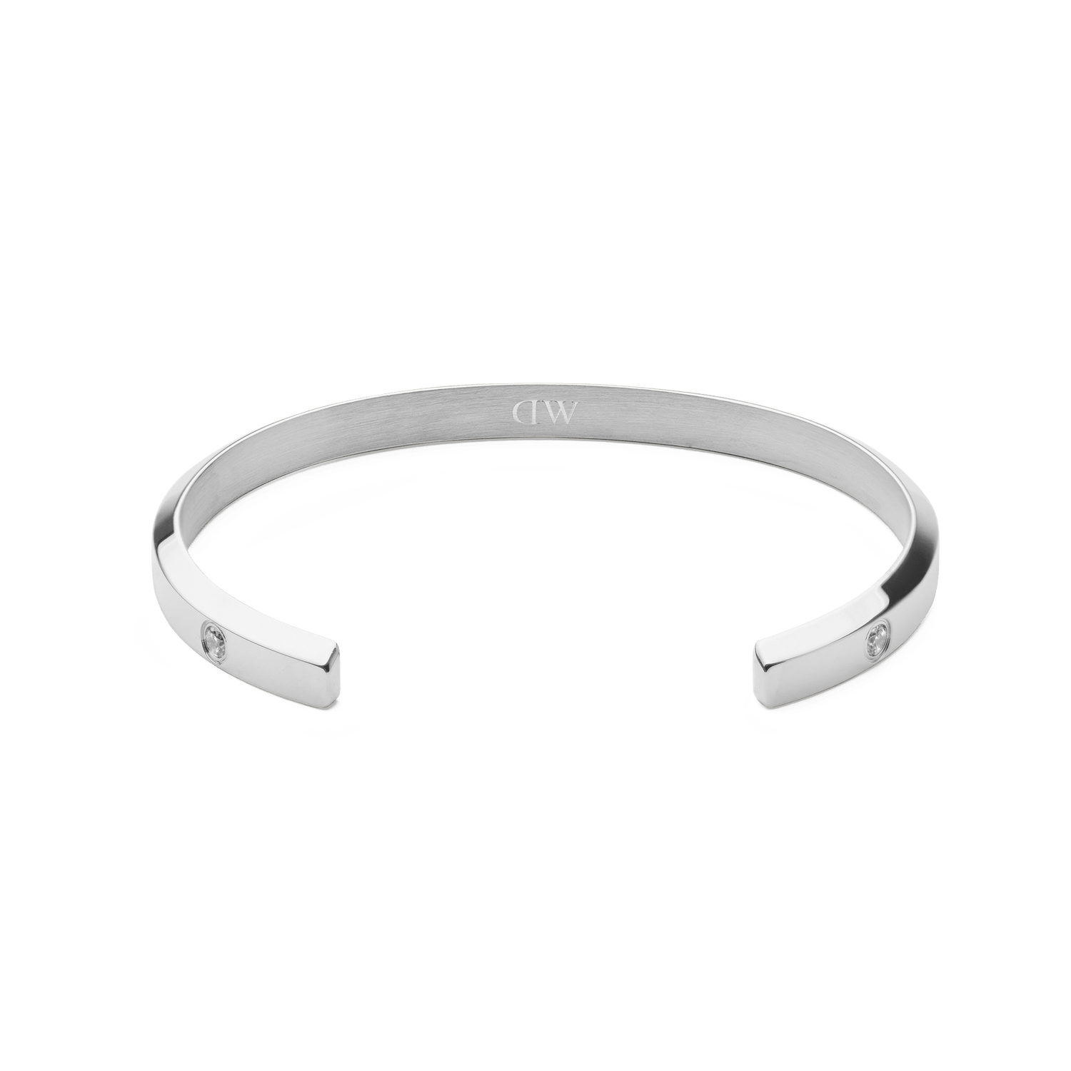 Classic Lumine Braceletシルバーの内側を正面から捉えた画像です。ヘアライン仕上げの内面中央にはDaniel Wellingtonのロゴが刻印され、両端にキュービックジルコニアがあしらわれたオープンカフデザインが特徴です。
