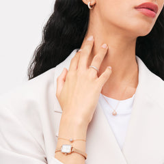 パヴェクリスタルペンダントネックレス ローズゴールドを着用したスタイリングイメージ。白のトップスとベージュのジャケットに合わせ、同コレクションのリング、イヤリング、ブレスレット、そしてローズゴールドの腕時計でトーンを統一したコーディネートです。