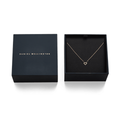 ダニエルウェリントンのギフトボックスに収められたMirelle Heart Necklace Rose Gold。箔押しのブランドロゴが施された蓋と、黒いクッションの上に丁寧にセットされたオープンハートのペンダントが、贈り物にぴったりの上品な仕上がりです。