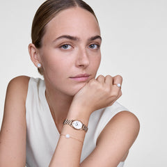 Audrey Ring Mother of Pearl Rose Goldを着用したスタイリングイメージです。同コレクションのイヤリングやブレスレット、ローズゴールドの腕時計と合わせ、マザーオブパールのトーンで統一したコーディネートをご紹介しています。