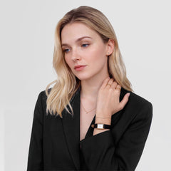 Mirelle Solitaire Necklace Goldを身に着けた女性のスタイリングイメージです。黒のジャケットの胸元に、細いゴールドチェーンと一粒のクリスタルが映え、ゴールドのリングやスタッドピアス、レクタンギュラーウォッチと合わせて上品にコーディネートされています。