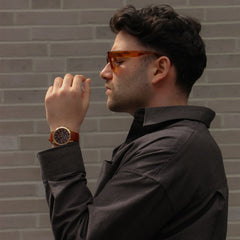 ダークトーンのシャツにIconic Chronograph St Mawesを合わせたコーディネート例。ブラウンのレザーストラップとローズゴールドケースが袖口から自然にのぞき、落ち着いた装いに上品なアクセントを加えています。