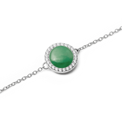 Audrey Bracelet Jade Silverの翡翠カボション部分をクローズアップした写真です。なめらかな曲面を描くグリーンの天然石が光を受け、深みのある色合いを魅せます。周囲を彩るホワイトキュービックジルコニアの繊細な輝きとシルバーチェーンが、美しく調和しています。