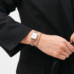 Tide Mesh Bracelet Melrose 2.8をローズゴールドのQuadro腕時計と重ね付けしたスタイリング例。ブラックのジャケットに、メッシュ素材の質感が統一された手元が引き立ちます。