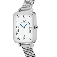 Quadro Sterling Roman Numerals Dateのダイヤルをクローズアップした画像です。ホワイトのギョーシェ模様にローマ数字のインデックス、IPブルーの時分針、6時位置の日付窓が鮮明に捉えられています。シルバーのプレスメッシュストラップとリューズも一緒に写っています。