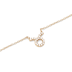 牡牛座のシンボルをクリスタルで表現した「Crystal Zodiac Chain Necklace Gold」のペンダント部分をクローズアップした画像です。丸みを帯びたモチーフと上部のラインに沿って、透明感のあるクリスタルがゴールドの爪留めで丁寧にセットされています。細身のチェーンと合わせることで、上品な輝きを演出します。