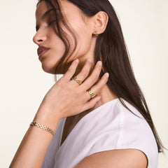 ダニエルウェリントンの3-Link Bracelet Goldを手首に着用した女性モデルのスタイリング画像です。同じLinkコレクションのゴールドリングとイヤリングを合わせ、統一感のある上品な装いを演出しています。