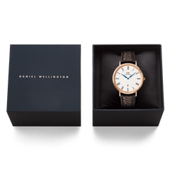 ダニエルウェリントン Classic Roman Numerals Date Dark Brown Croc Belly Rose Goldをネイビーのブランドギフトボックスに収めた画像です。ホワイト文字盤にブルーの針とローマ数字が映え、ギフトや特別な贈り物にぴったりのパッケージングとなっています。