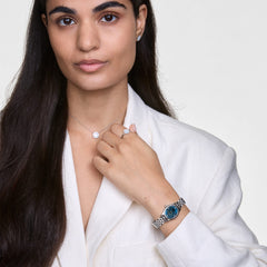 オフィーリア ミニ アークティックシルバーを着用した女性のスタイリングイメージ。白いリネンシャツにブルーダイヤルのオーバル型腕時計を合わせ、シルバーのネックレスやリング、ピアスでコーディネートしています。