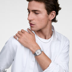 白いシャツを着た男性が、Marlon Wire Linen Silverを手首に着用したスタイリング例です。クッション型のシルバーケースとワイヤーメッシュバンドが、シルバーのリングやネックレスと調和し、清潔感のあるコーディネートを演出します。
