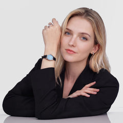 ブラックのジャケットを着た女性がOphelia Mini Black Lizard Ice Blue Guilloché Silverを身に着けた様子です。アイスブルーのオーバル文字盤とブラックレザーストラップが、上品な装いに自然に調和しています。