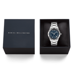 ダニエルウェリントンのネイビーのギフトボックスに収められたIconic GMT Link Brushed Bezel Silverです。ブルーの文字盤を持つシルバーモデルがブラッククッションの上に丁寧にセットされ、贈り物にぴったりの上品なパッケージングとなっています。