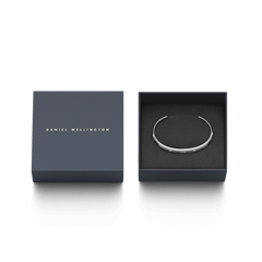 ダークネイビーの専用ギフトボックスに収められたClassic Lumine Bracelet Sです。ブラックのクッション上にシルバーカラーのオープンカフが丁寧にセットされ、蓋にはDaniel Wellingtonのロゴが箔押しされています。贈り物にも最適な上品なパッケージです。