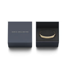 Daniel Wellington Elan Braceletのゴールドカフブレスレットが、ネイビーのブランド専用ギフトボックスに収められています。ブラックのクッション上にブレスレットが丁寧にセットされ、贈り物にふさわしい上品な仕上がりです。