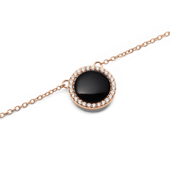 Audrey Necklace Black Agathe Rose Goldのペンダント部分をクローズアップした画像です。ドーム型の黒メノウが光を受けて深い輝きを放ち、周囲を囲むホワイトキュービックジルコニアのヘイローとローズゴールドのチェーンが繊細なコントラストを演出しています。