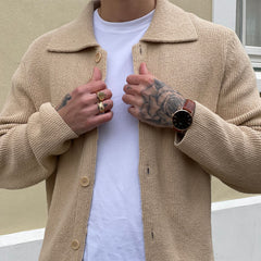 ベージュのニットジャケットと白のTシャツを合わせた男性の手元に、Daniel Wellington Classic St Mawesのローズゴールドケースとブラウンレザーストラップが自然に馴染む着用イメージです。