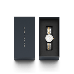 ダニエルウェリントンのPetite Lumine Bezel 5-Link Two-Tone MOPが、ネイビーのブランドギフトボックスに収められています。箱の蓋にはゴールドのブランドロゴが縦にあしらわれ、内側のブラッククッションの上には、クリスタルベゼルとツートーンブレスレットの腕時計が美しくセットされています。