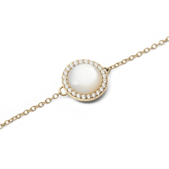 Audrey Bracelet Mother of Pearl Goldのチャーム部分をクローズアップした画像です。ドーム型のマザーオブパールが放つ乳白色の優美な光沢と、周囲を彩るホワイトキュービックジルコニアの繊細な輝き、ゴールドトーンのチェーンの細やかなディテールがご覧いただけます。