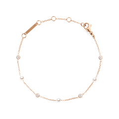 ダニエルウェリントンのPearl Bracelet Rose Gold。細いローズゴールドチェーンにパールとクリアストーンが交互にあしらわれ、ブランドロゴ入りのプレートとロブスタークラスプが付いています。