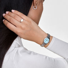 Classic Mini Signet Ringのシルバーを薬指に着用したスタイリング例です。シルバーのDaniel Wellington腕時計やフープピアスと合わせ、統一感のあるコーディネートを楽しめます。