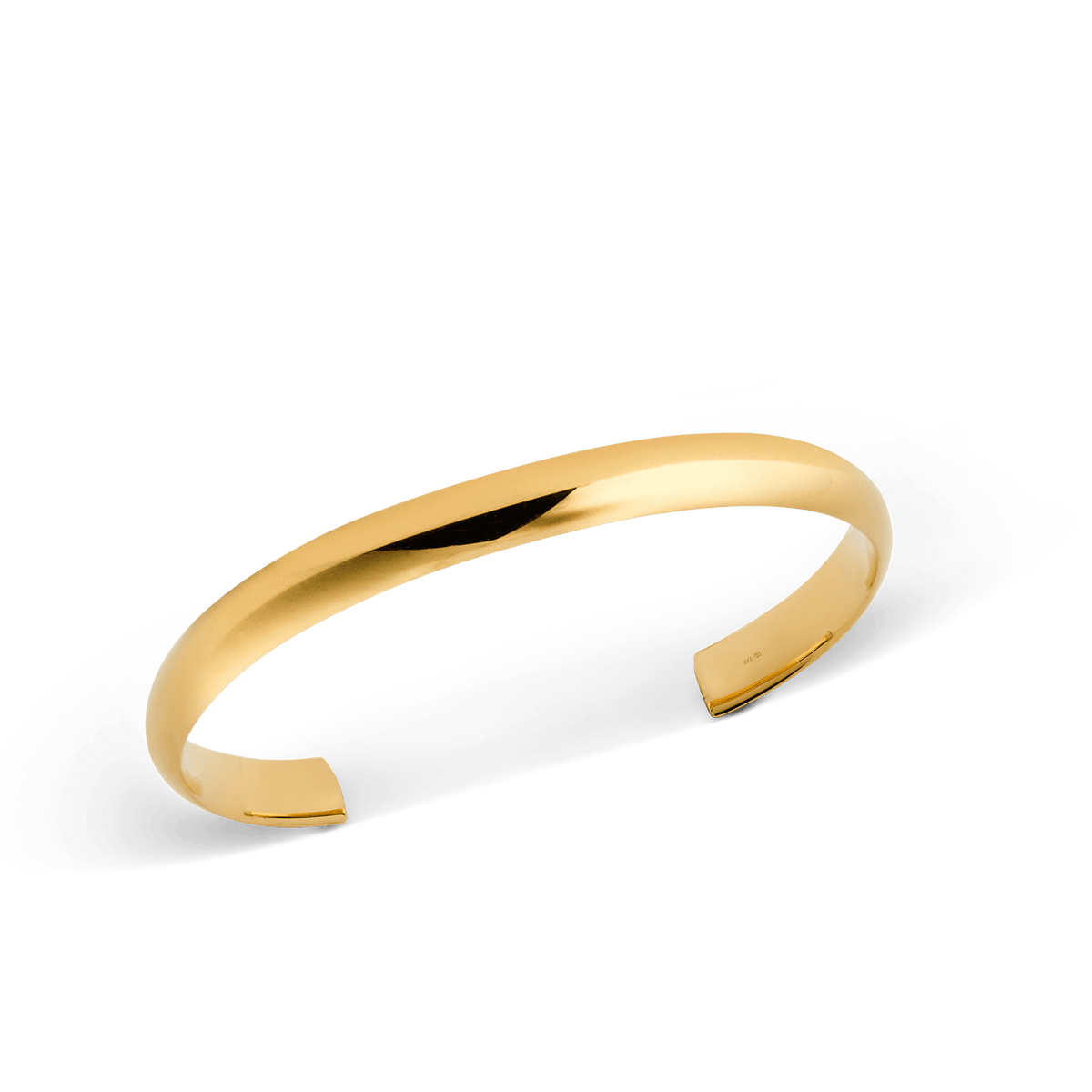 Arch Cuff Gold 6mmを斜めからとらえたクローズアップ画像です。光を受けて輝くポリッシュ仕上げのゴールドカラーと、内側に施された控えめな刻印が確認できます。