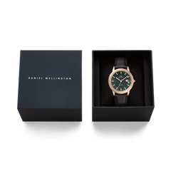 ダニエルウェリントンの「Iconic Sheffield Automatic Rose Gold」をネイビーカラーのギフトボックスに収めた贈り物に最適なセットです。エメラルドグリーンの文字盤とブラックレザーストラップの腕時計が、ブラックのクッションの上に丁寧にセットされており、上品な仕上がりとなっています。