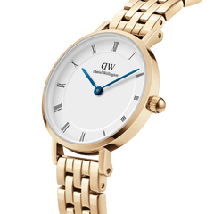 Petite Roman Numerals 5-Link Goldを斜めからクローズアップした画像です。ゴールドケースのポリッシュ仕上げや、丸みを帯びたリューズのディテール、ブルースチールの針とローマ数字が映えるホワイトダイヤルがご覧いただけます。