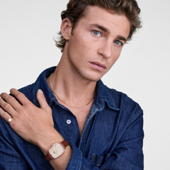 デニムシャツを着用した男性が、Daniel WellingtonのMarlon ローズゴールドをブラウンレザーストラップで身に着け、薬指にはClassic Mini Signet Ringを重ねたスタイリングイメージです。