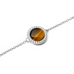 Audrey Bracelet Tiger Eye Silverのタイガーアイ部分をクローズアップした画像です。光の当たり方によって琥珀色から深い焦げ茶色へと変化するドーム型の天然石と、その周囲を彩るホワイトキュービックジルコニアの繊細な輝きが際立っています。