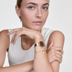 Petite Reflection Rose Goldを身に着けた女性のスタイリングイメージです。ローズゴールドのメッシュストラップとミラーダイヤルが手元でやわらかな輝きを放ち、同系色のブレスレットと重ね付けすることで、統一感のあるコーディネートを演出しています。