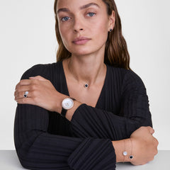 Audrey Black Agatheコレクションのリング、ネックレス、イヤリング、ブレスレットをローズゴールドの腕時計と合わせたコーディネート例です。黒のVネックトップスに、ブラックアゲートのジュエリーを揃えることで、統一感のある洗練されたスタイリングが際立ちます。